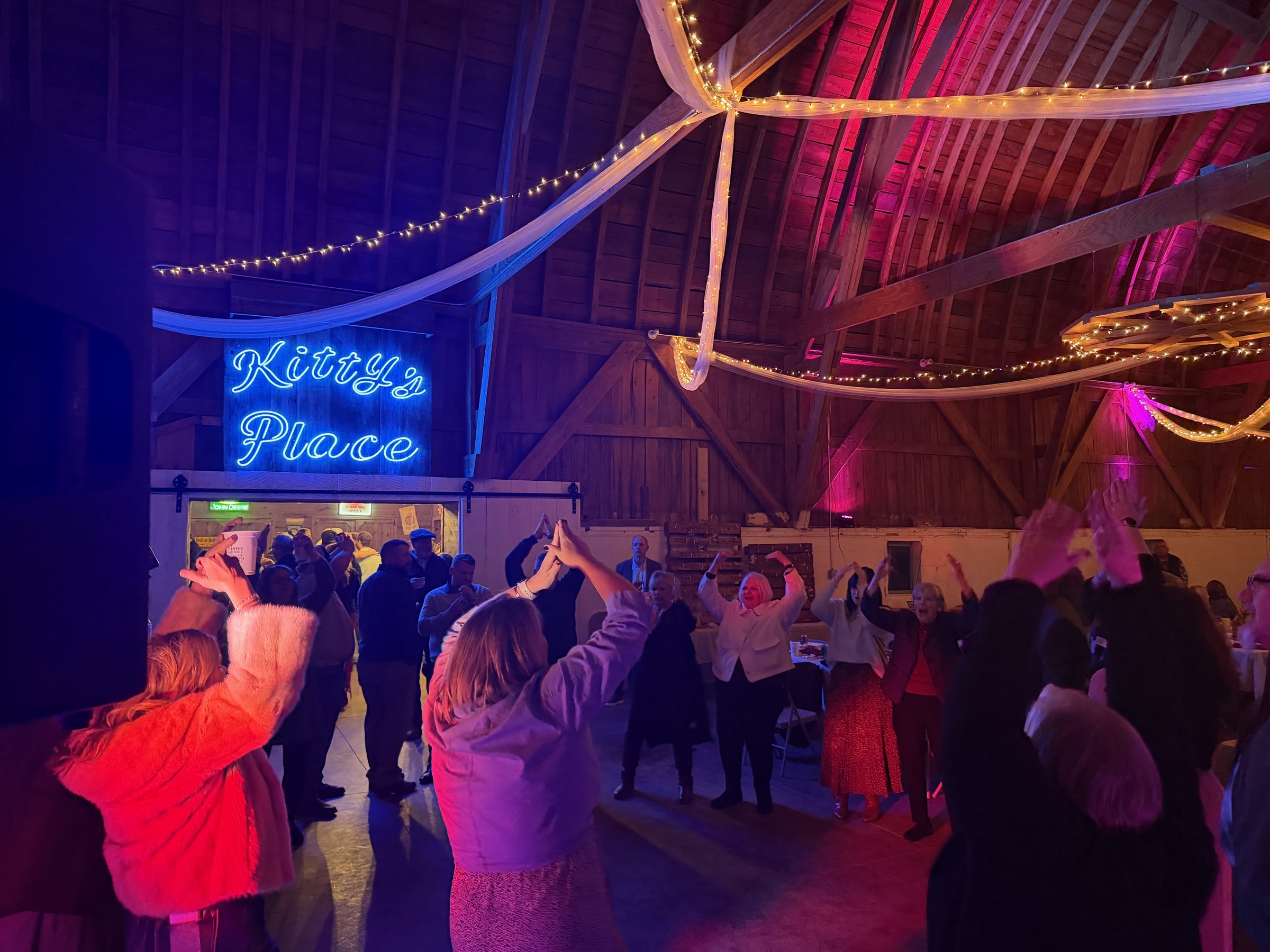 Wedding guests celebrating together in a warmly lit barn