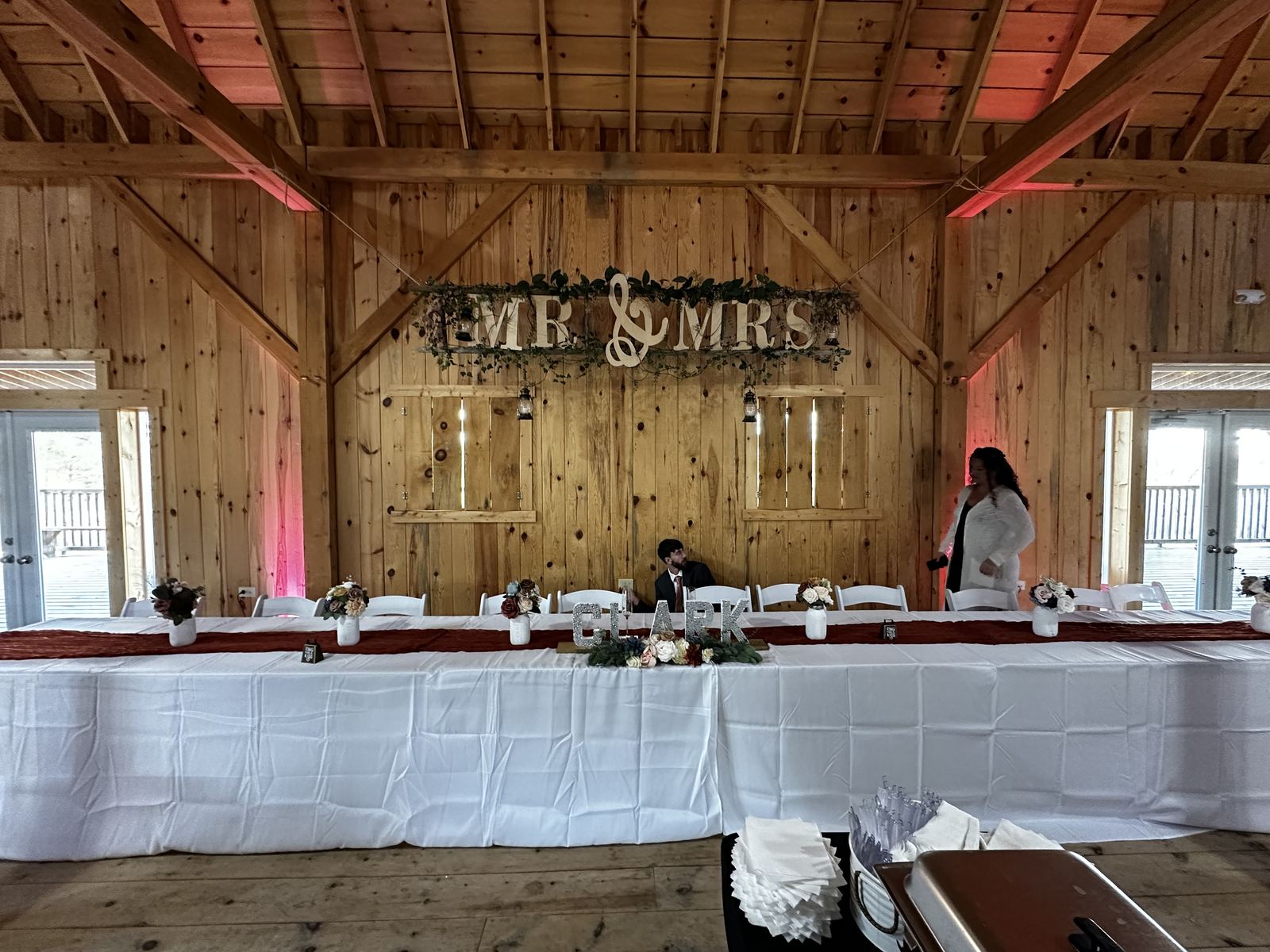 Decorated head table inside a warmly lit barn reception