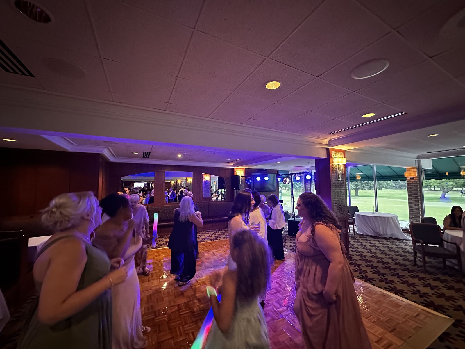 Wedding crowd celebrating under colorful reception lighting