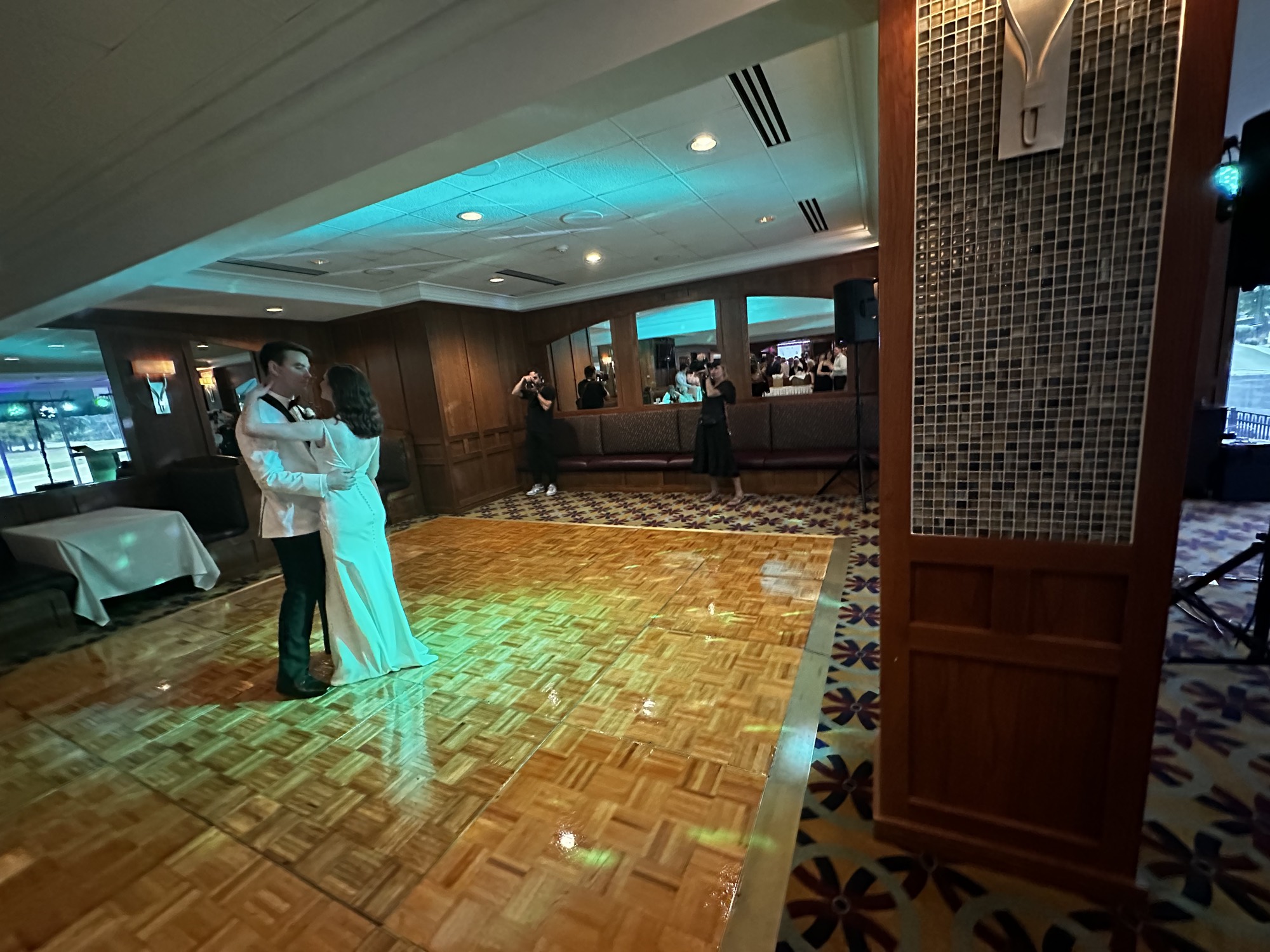 Newlyweds sharing a first dance under green lighting