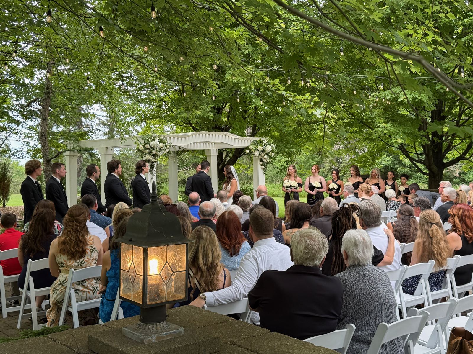Wide view of an outdoor wedding ceremony surrounded by trees
