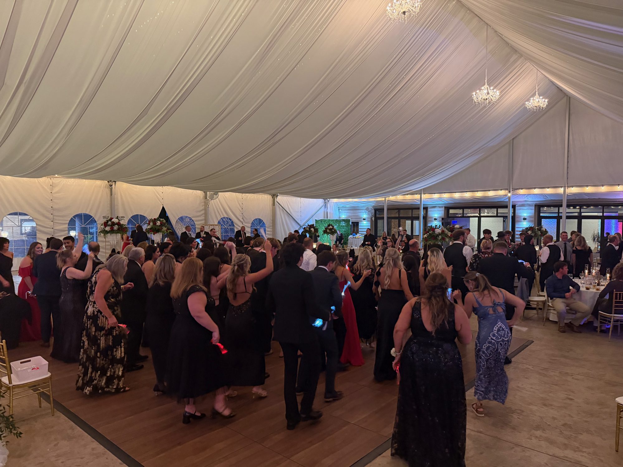 A large crowd dancing together inside a waterfront wedding tent