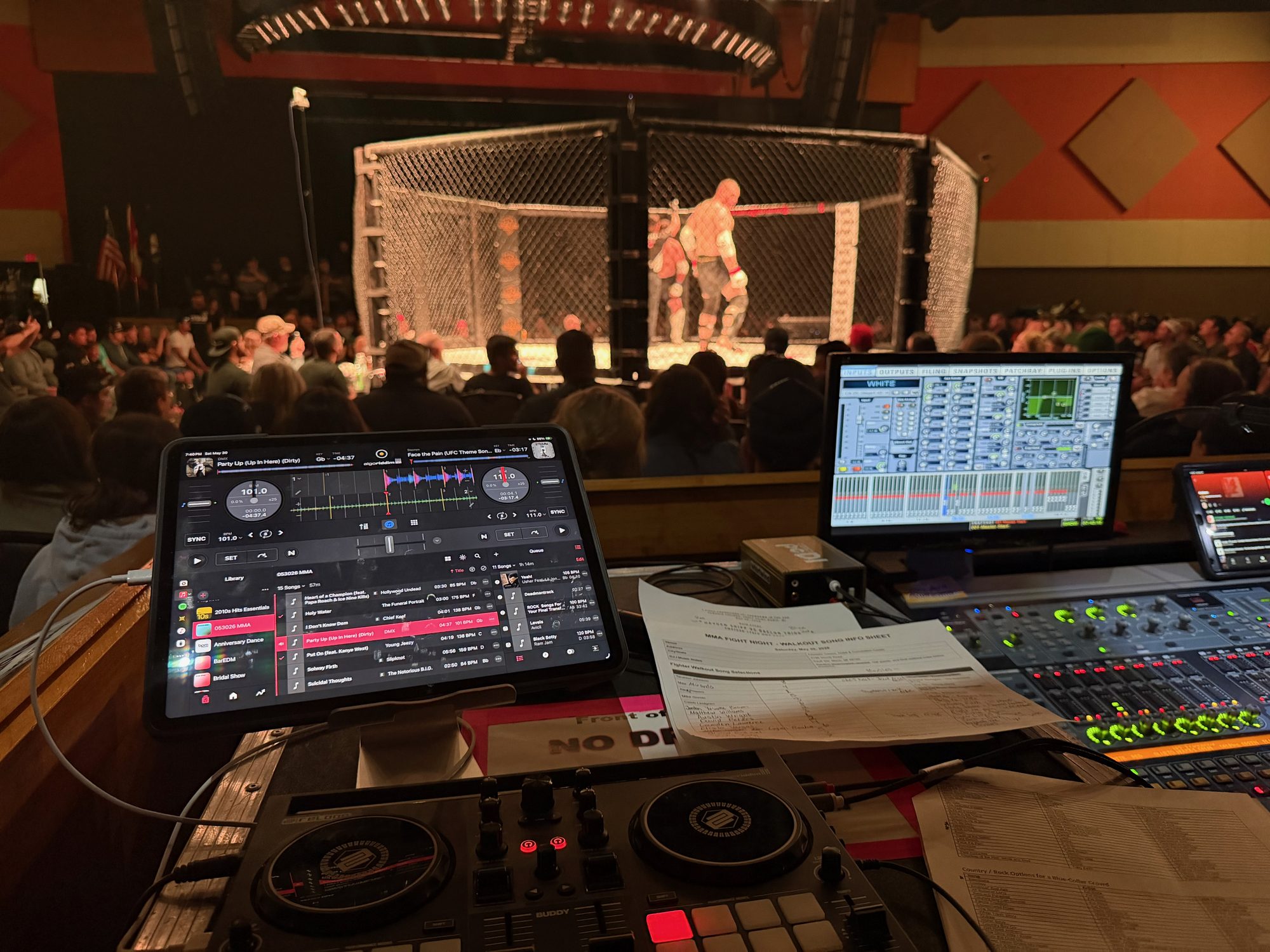 DJ and production controls facing a live MMA cage