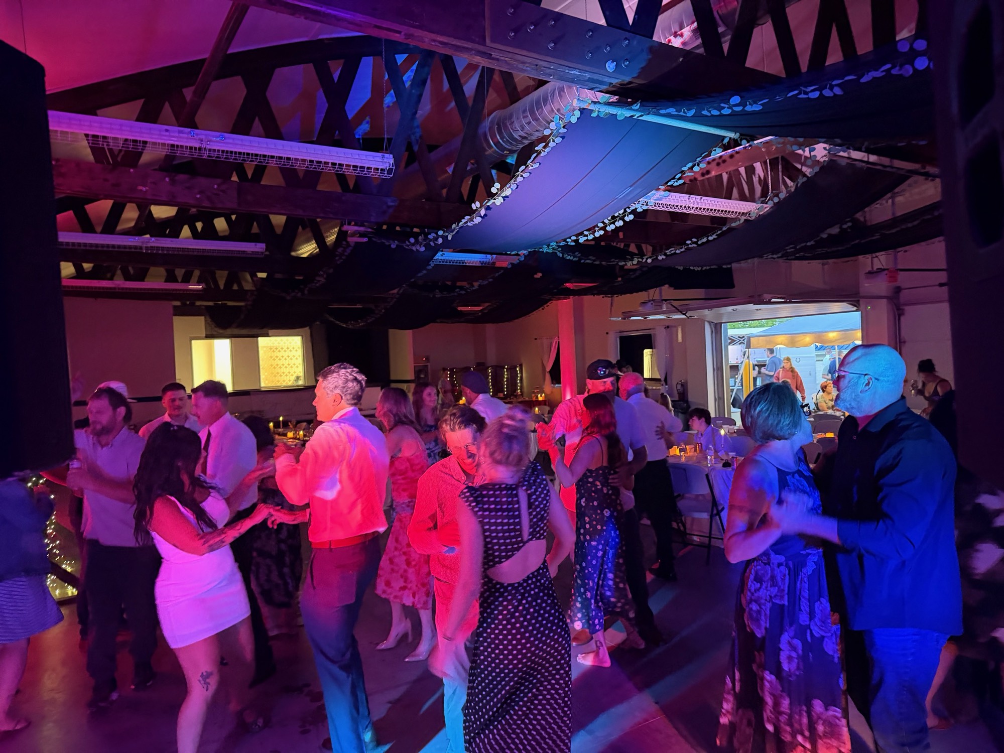 Wedding guests dancing in a room washed with red and blue uplighting