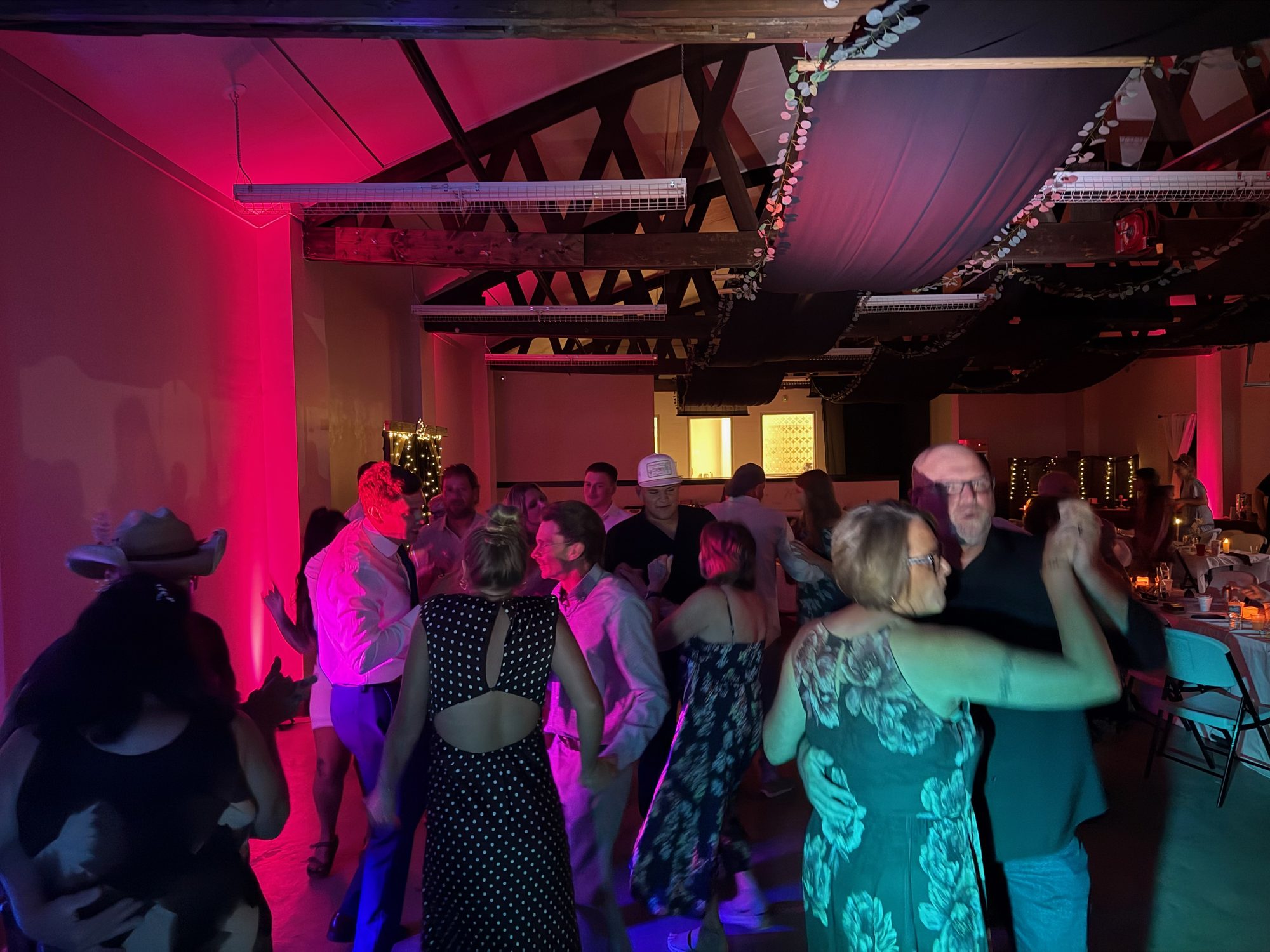 Wedding guests filling a dance floor under rich red lighting