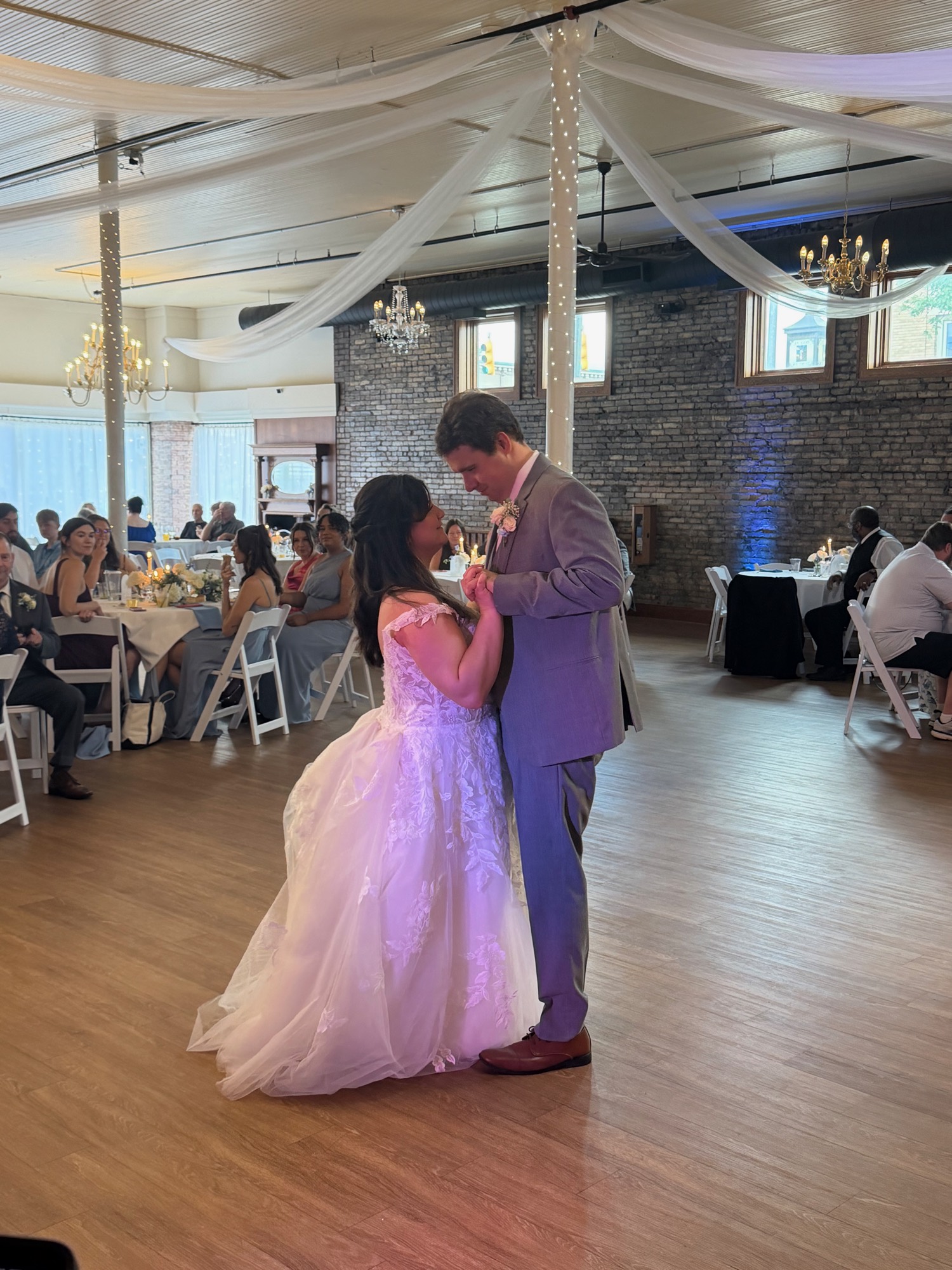 Newlyweds sharing their first dance in front of seated guests