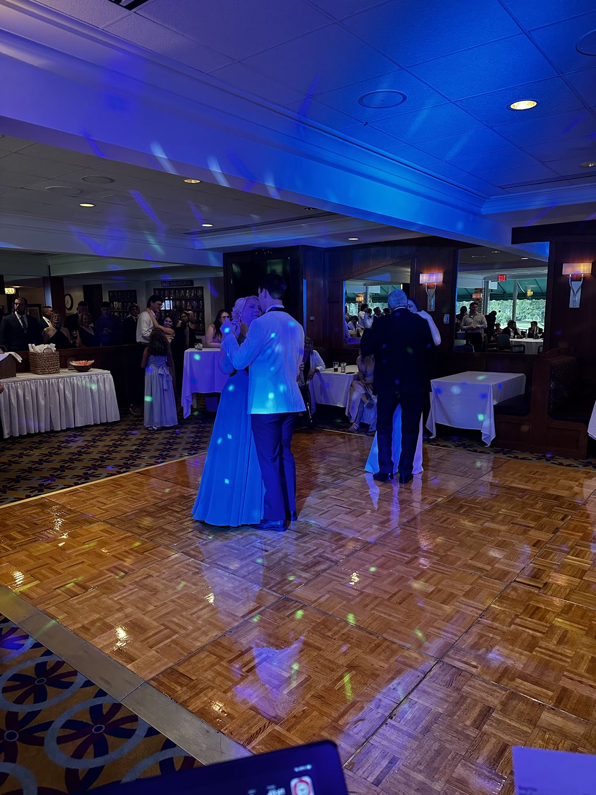 Reception guests dancing beneath colorful lighting