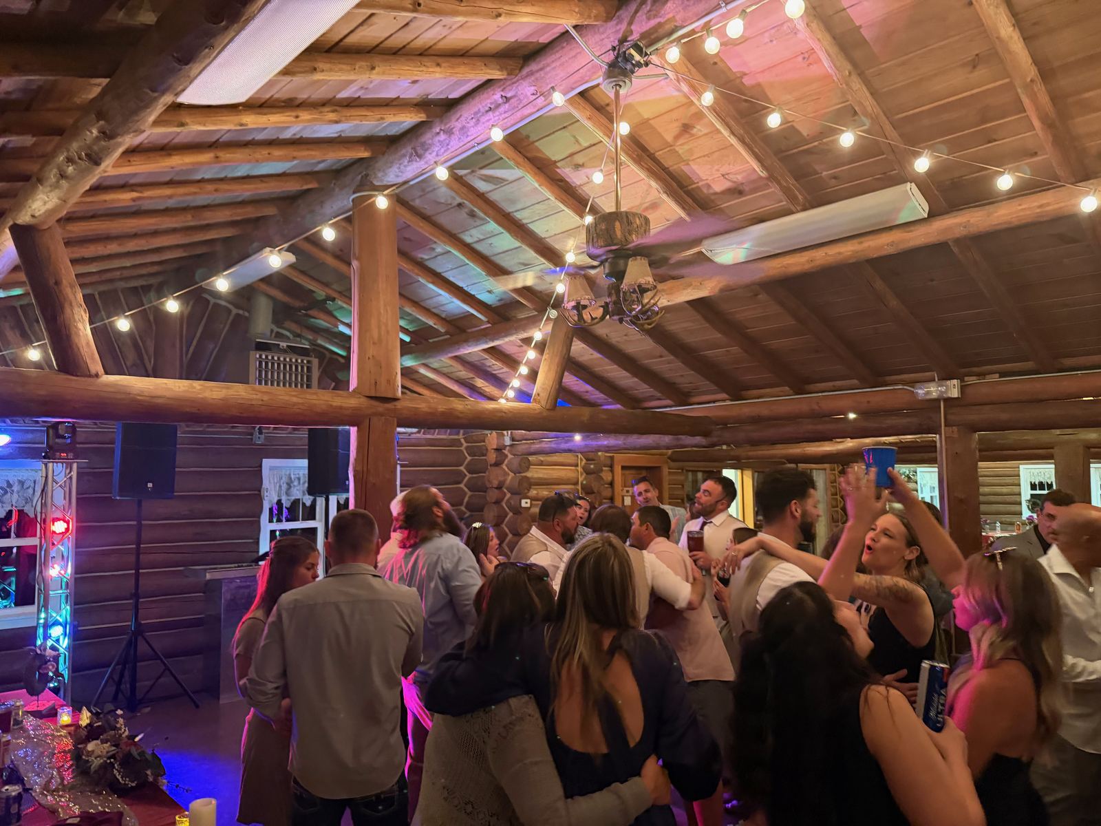 Guests crowding a rustic wood-lined wedding dance floor