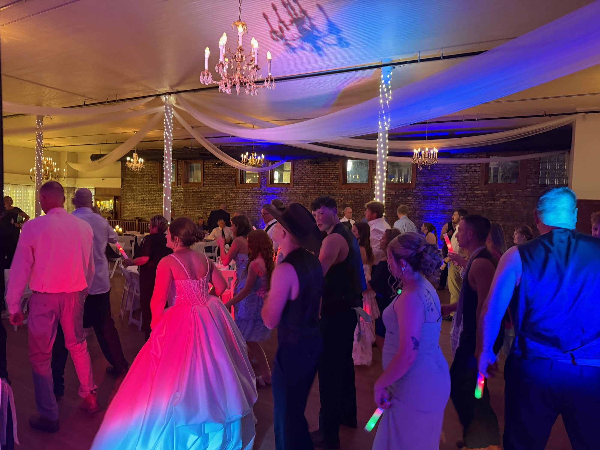 A bride and guests celebrating beneath blue and pink lights