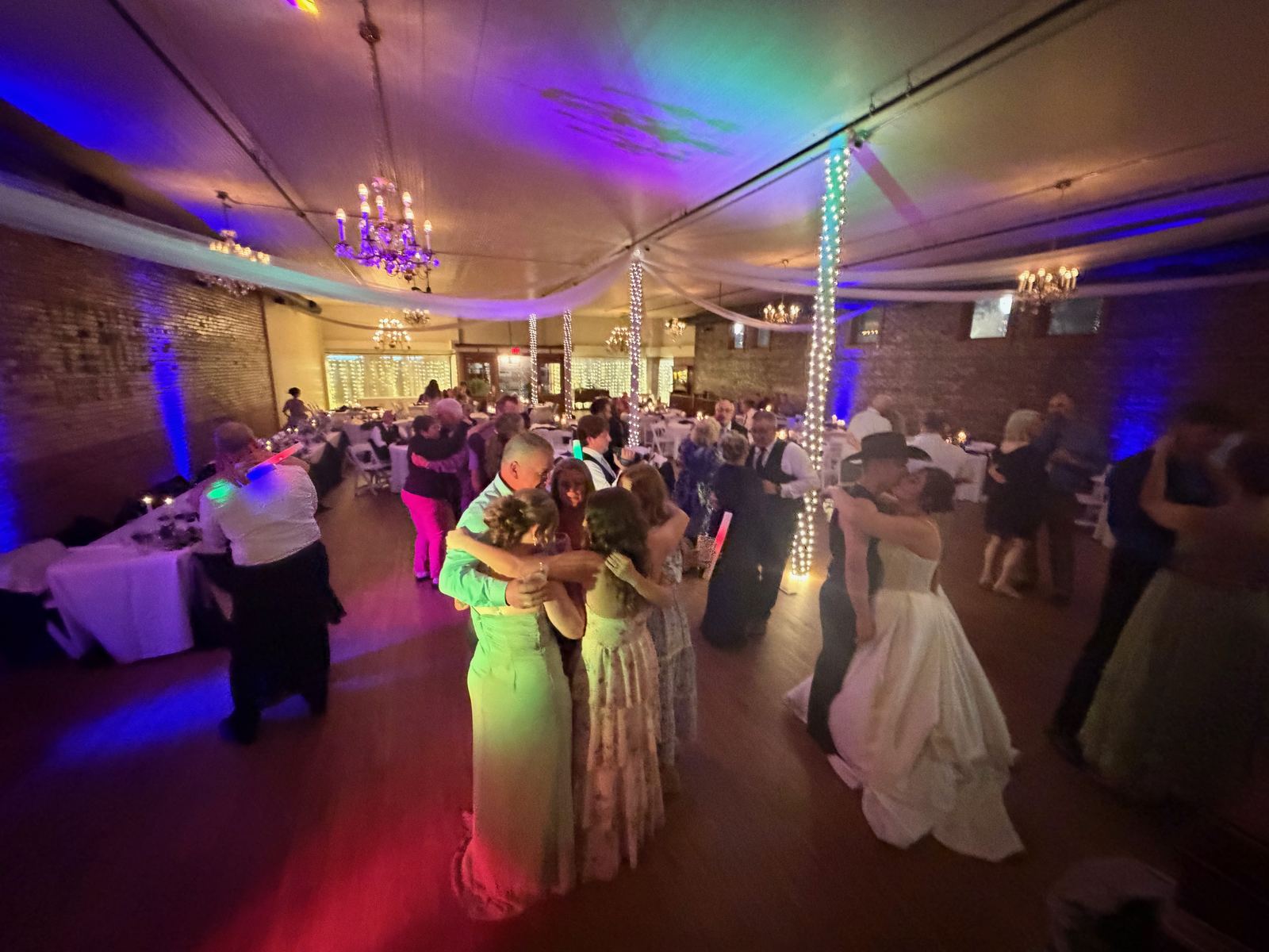 Colorfully lit wedding dance floor viewed from beside the crowd
