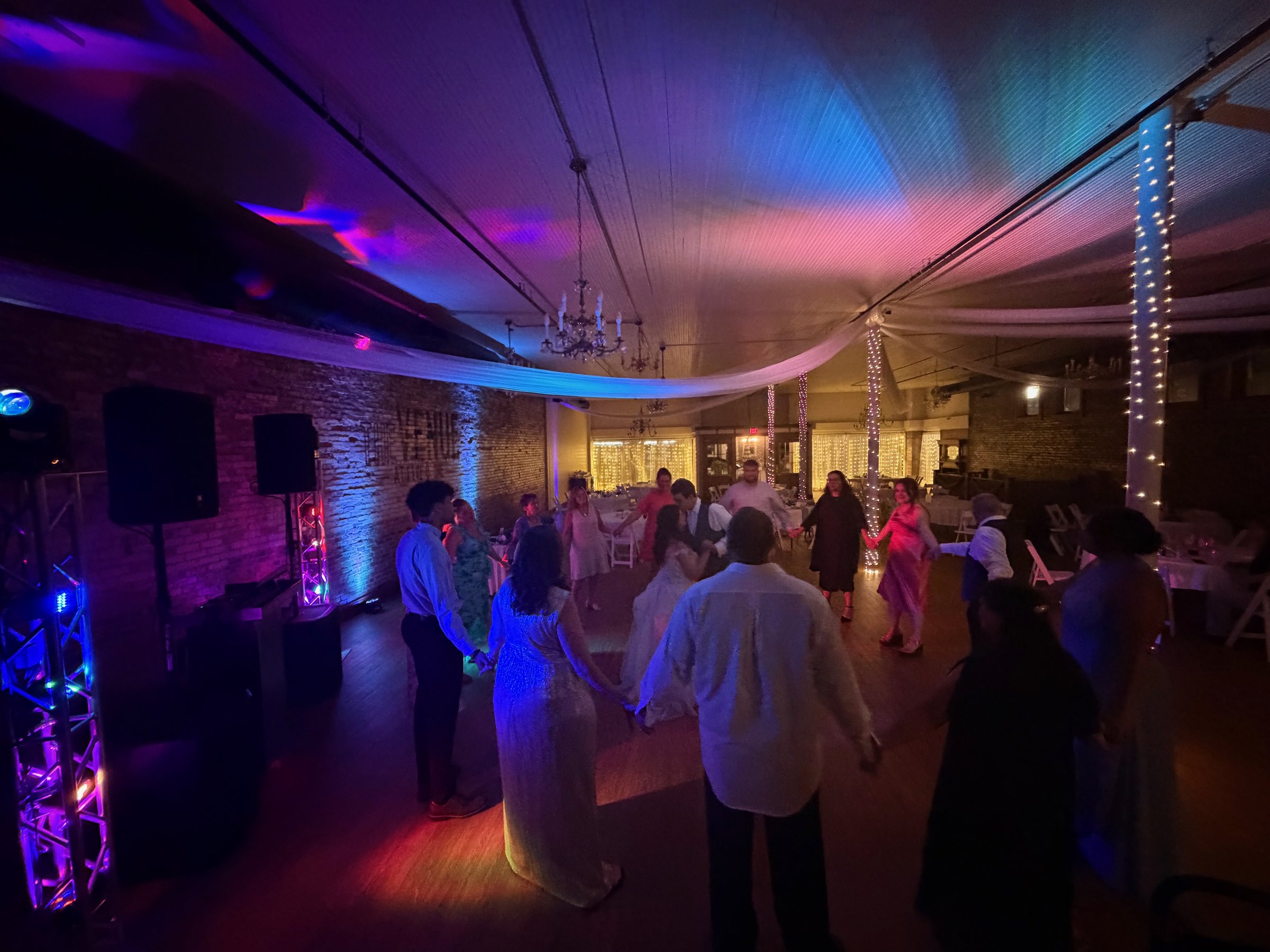 Guests dancing in a barn beneath blue and magenta lighting