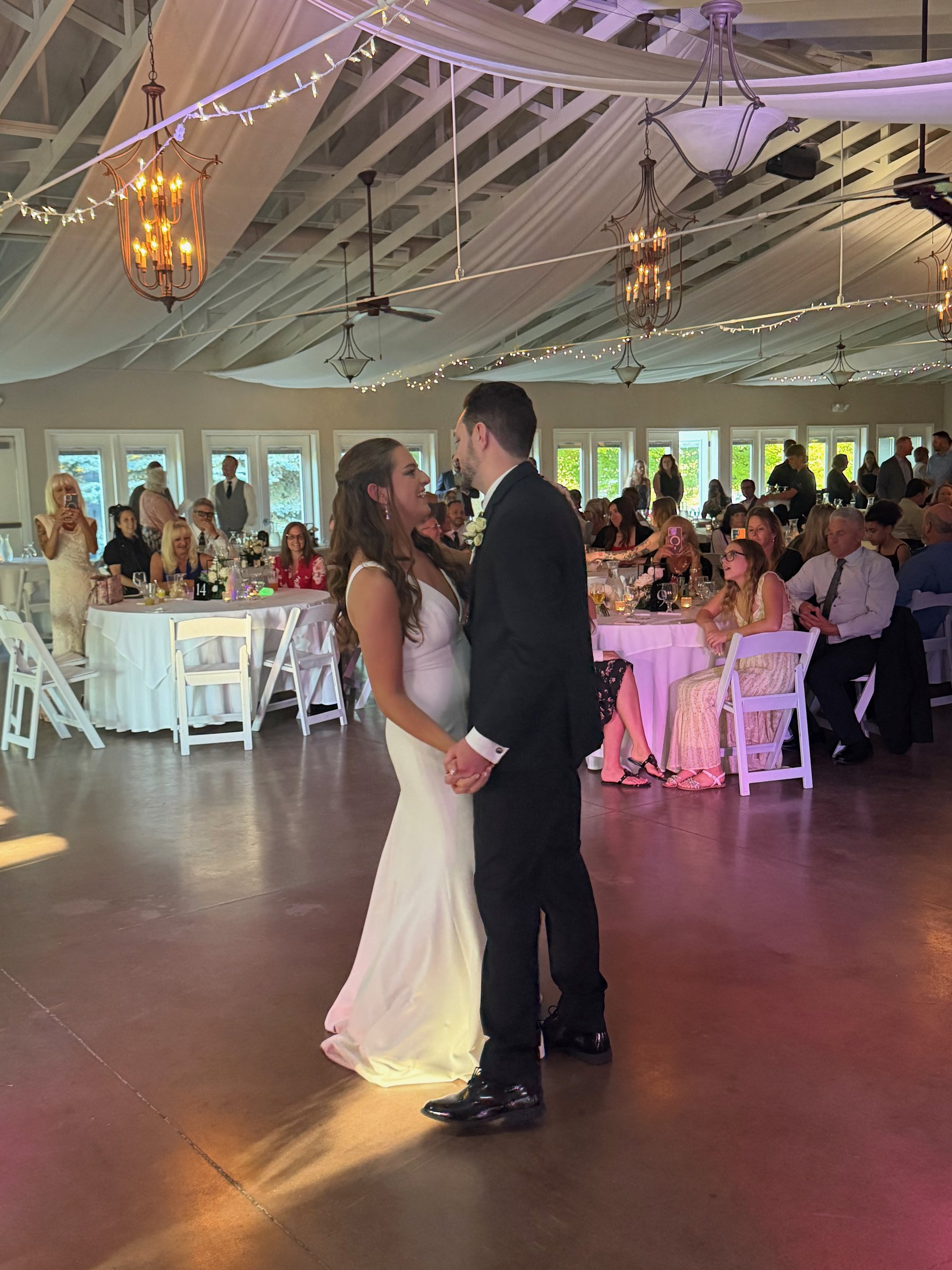 Newlyweds sharing their first dance while family and friends look on