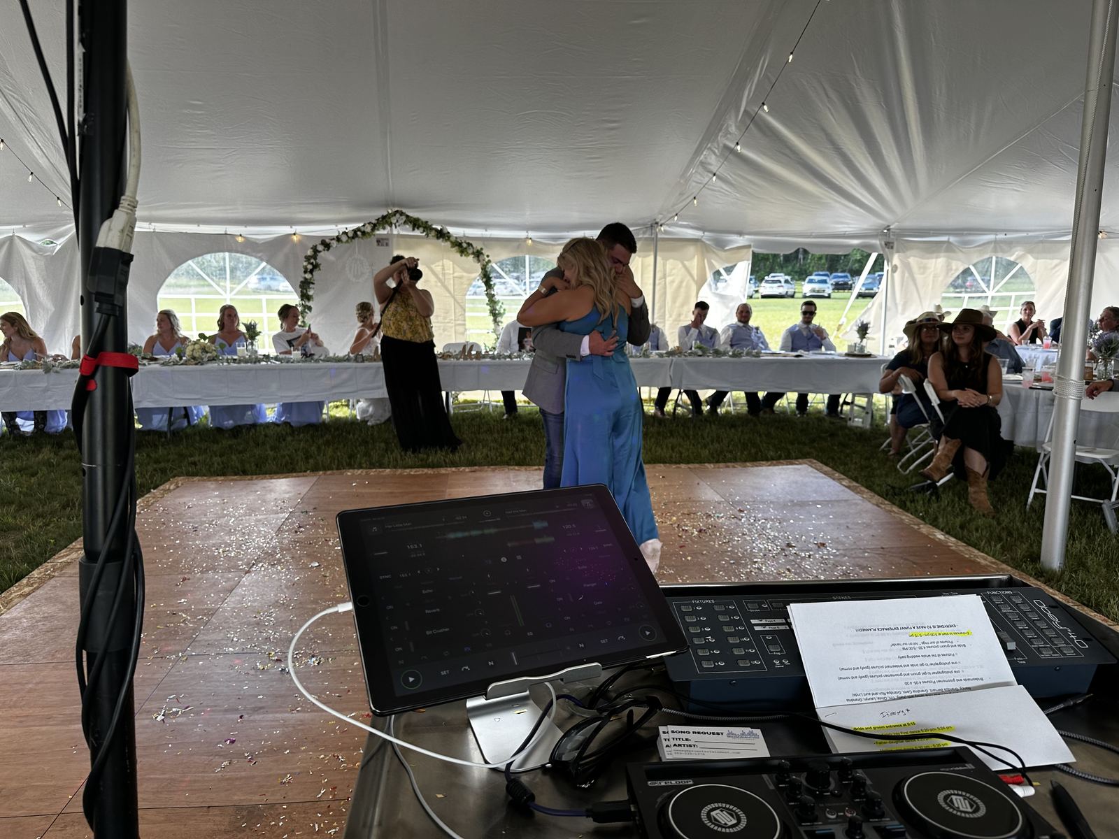 Wedding crowd dancing under string lights inside a tent