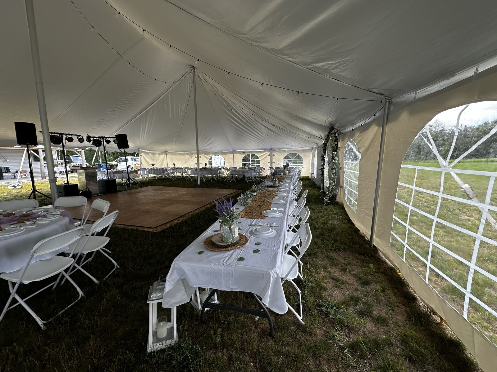 Wide view of the DJ area and open dance floor beneath a wedding tent