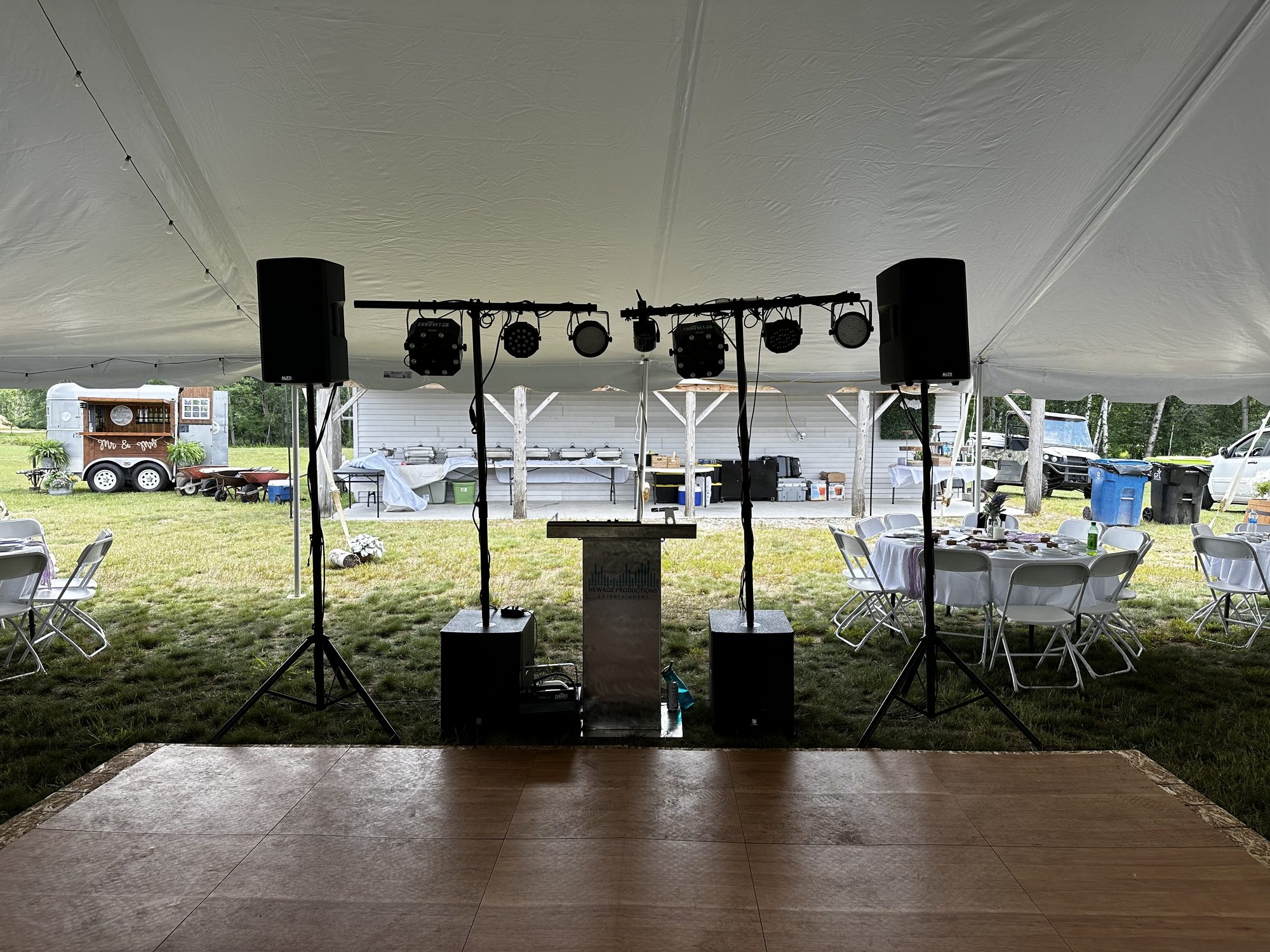 DJ booth, speakers, and lighting arranged beneath a white wedding tent