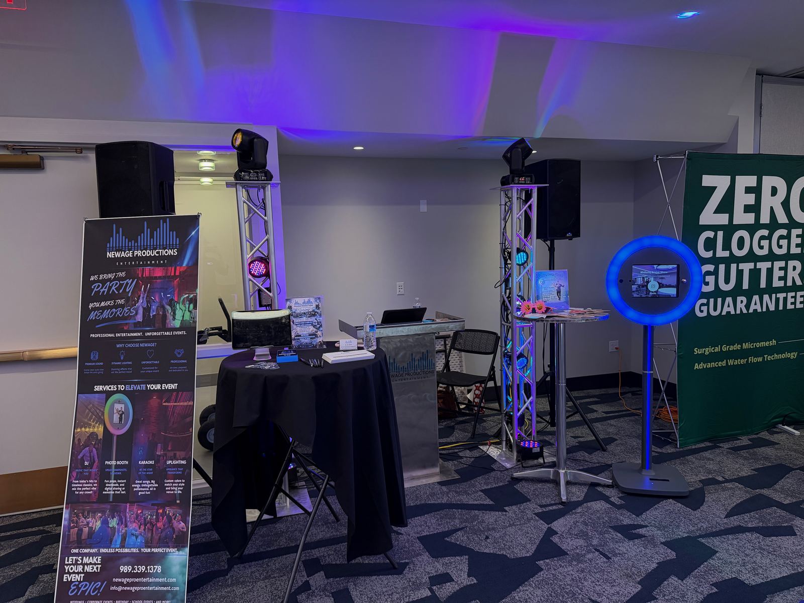 NewAge wedding expo booth with DJ equipment, photo booth, and printed displays