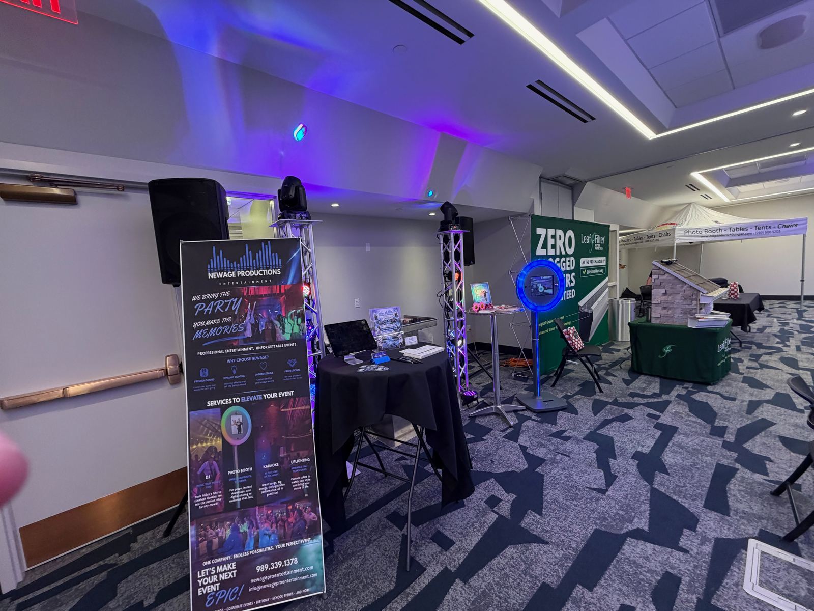 A side view of the NewAge wedding expo display with speakers, lighting, and service information