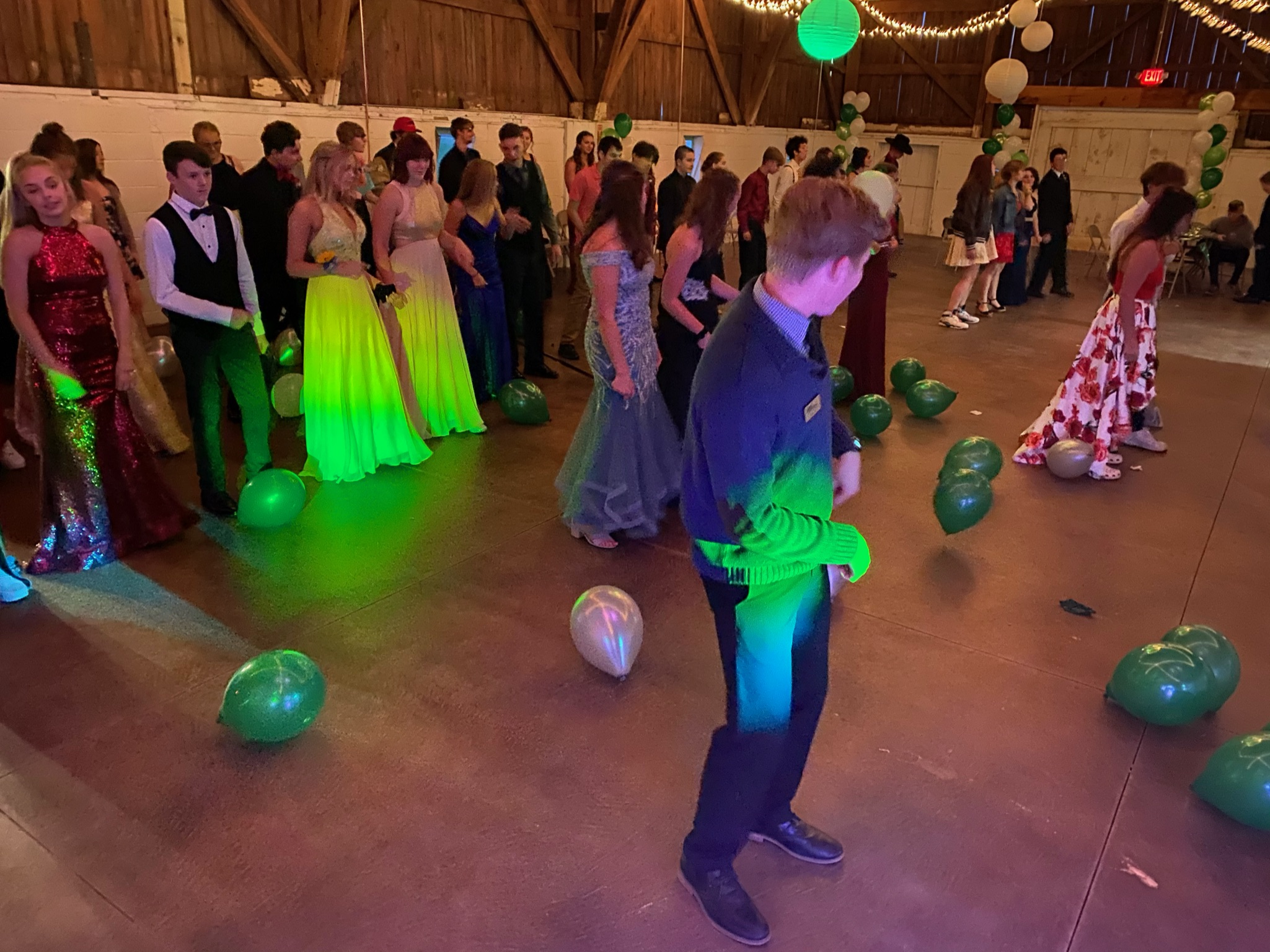Students filling a school dance floor beneath colorful lights
