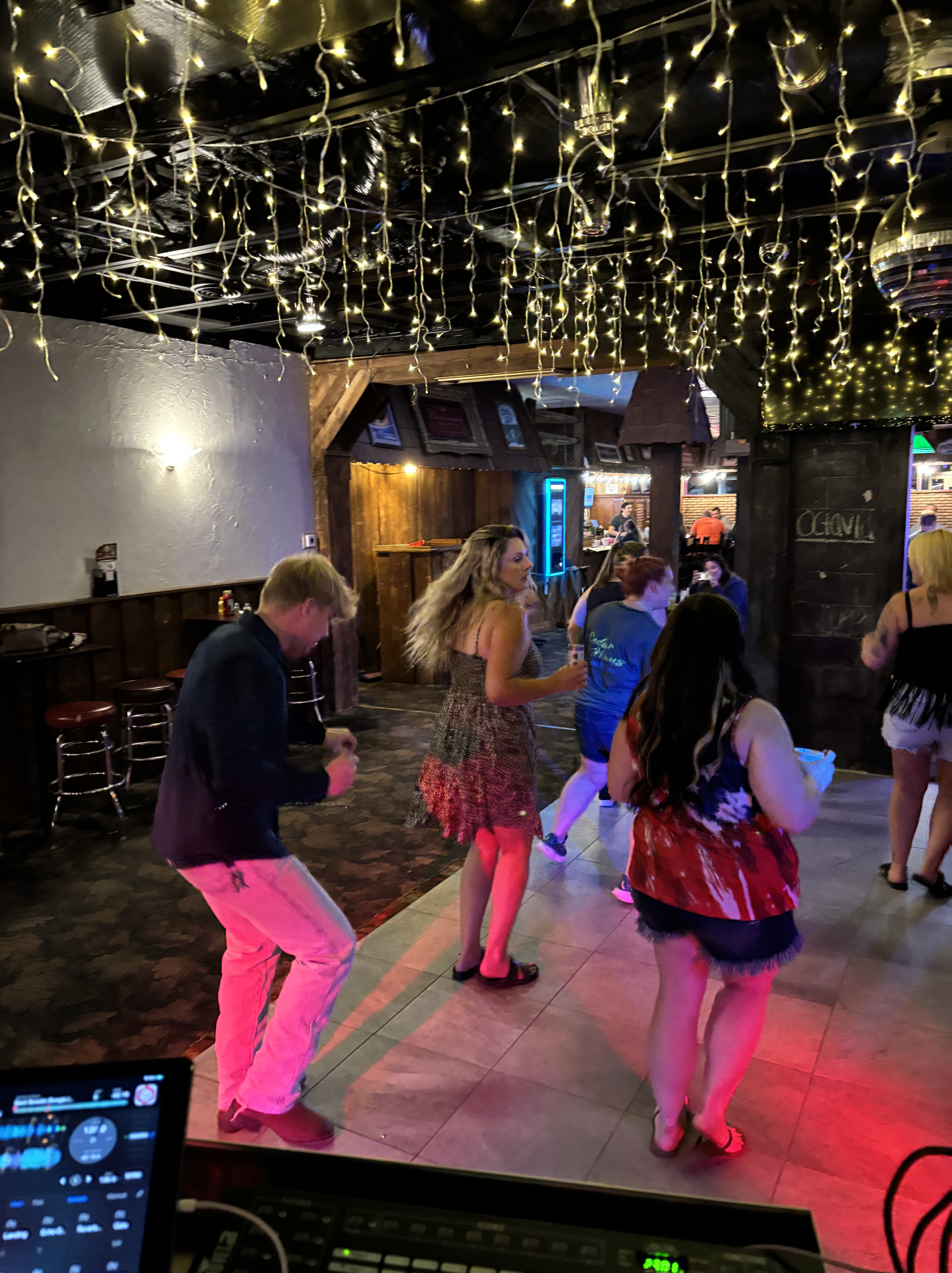 A lively bar crowd dancing beneath string lights